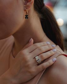 A woman wearing earrings and a ring on her finger