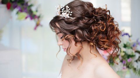 A woman with curly hair is wearing a crown on her head.