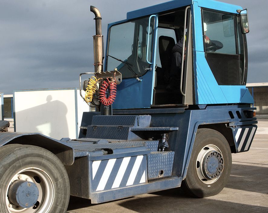 A blue truck with white stripes on the side is parked in a parking lot