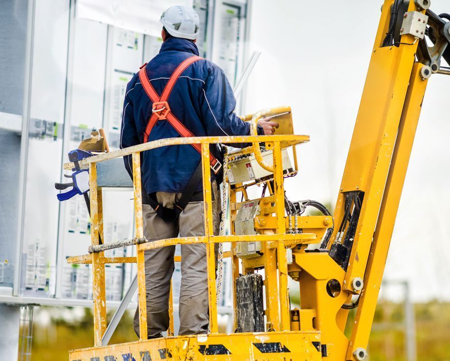 A man is standing in a bucket on a crane.