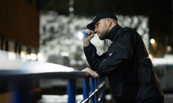 A man is leaning on a railing while talking on a cell phone.