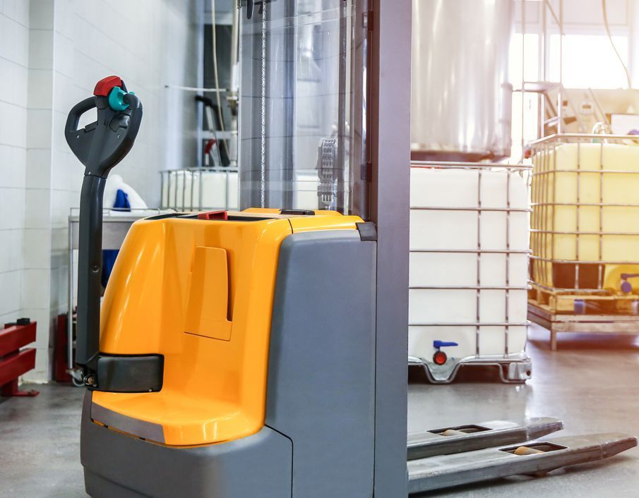 A yellow and gray forklift is parked in a warehouse.