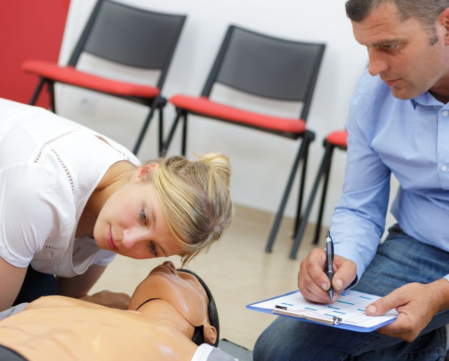 A man is writing on a clipboard while a woman looks at a mannequin.
