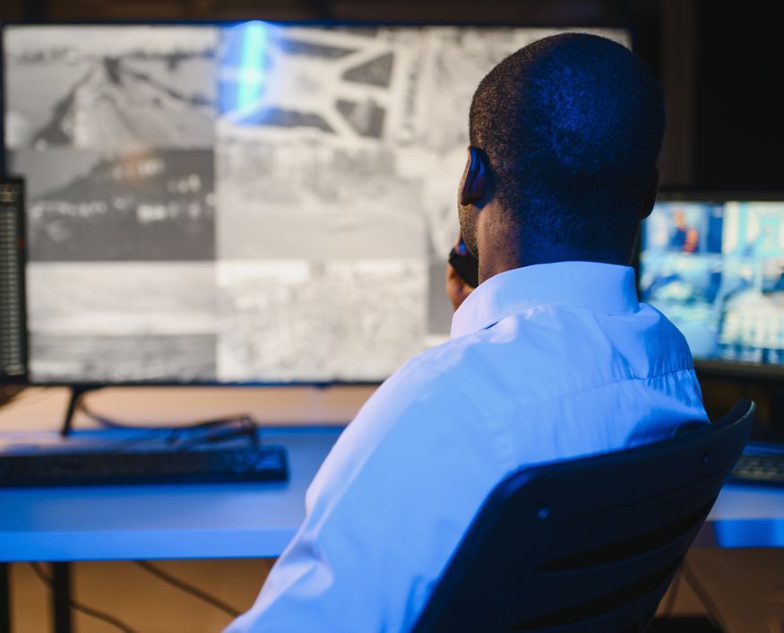 A man is sitting in front of a computer monitor.