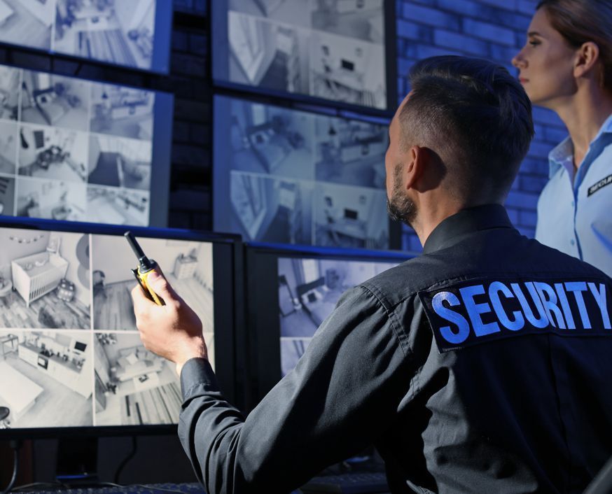 A man in a security uniform is looking at a computer screen.