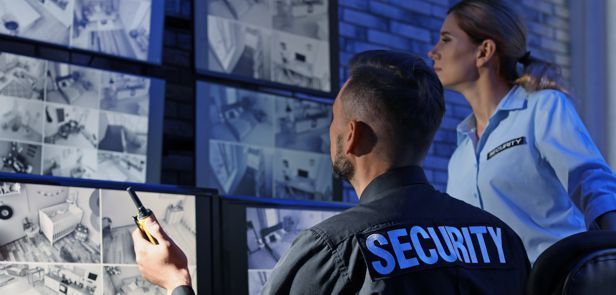 A man and a woman are looking at security cameras.
