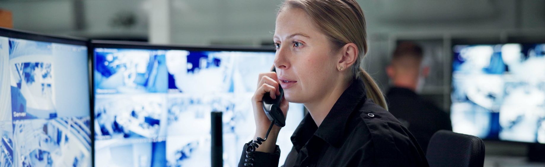 A woman is talking on a cell phone while sitting in front of a computer monitor.