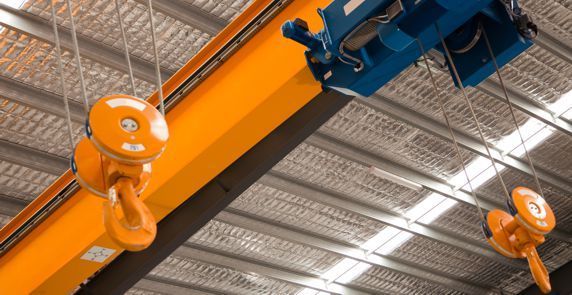 A crane is hanging from the ceiling of a warehouse.