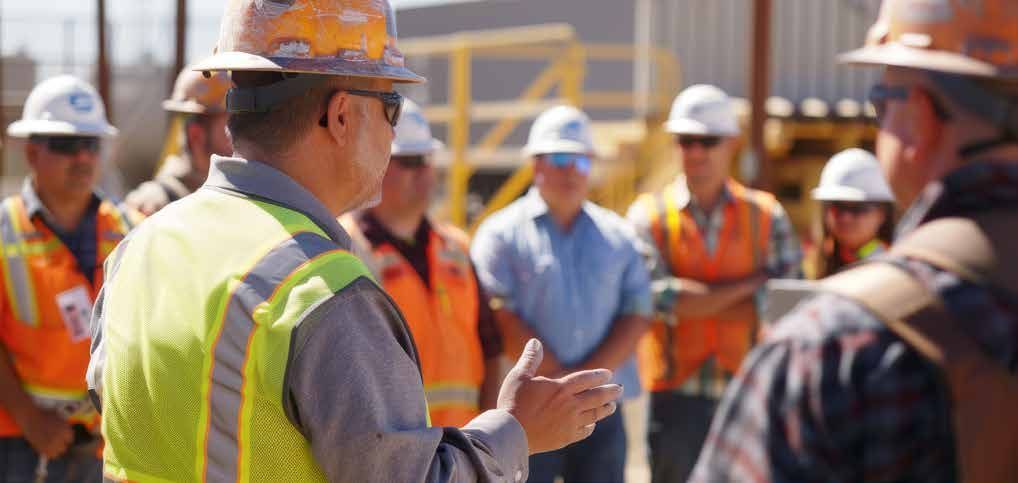 A man in a hard hat is talking to a group of construction workers.
