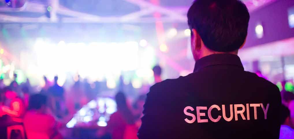 A security guard is standing in front of a crowd of people at a party.
