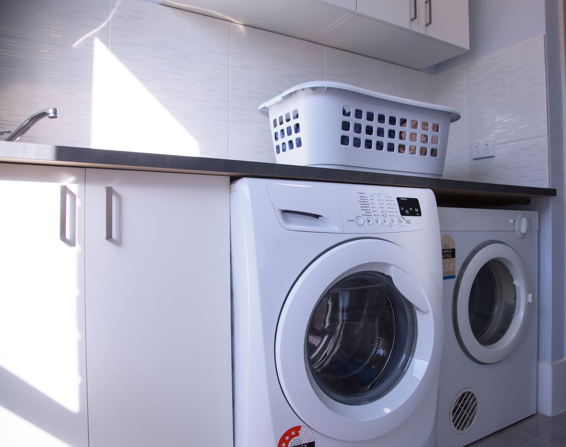 Laundry room with washing machine and dryer, shelves with towels, and a window.