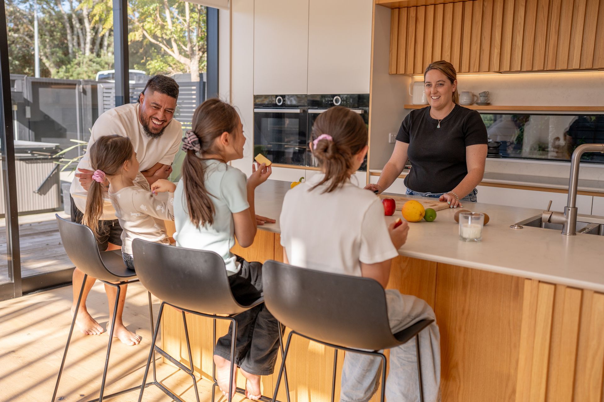 Modern kitchen with gray cabinets, wooden island, and four tan bar stools.