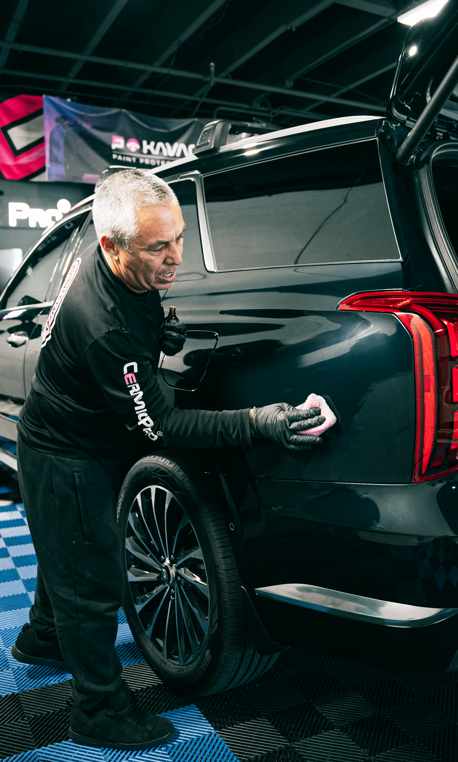 A man is cleaning the back of a black truck.