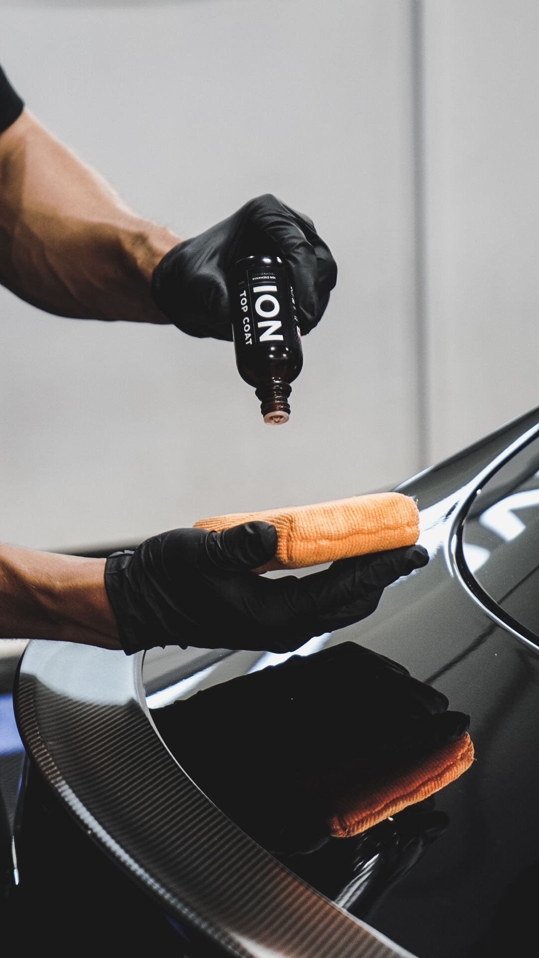 A person is applying a coating to a car with a sponge.