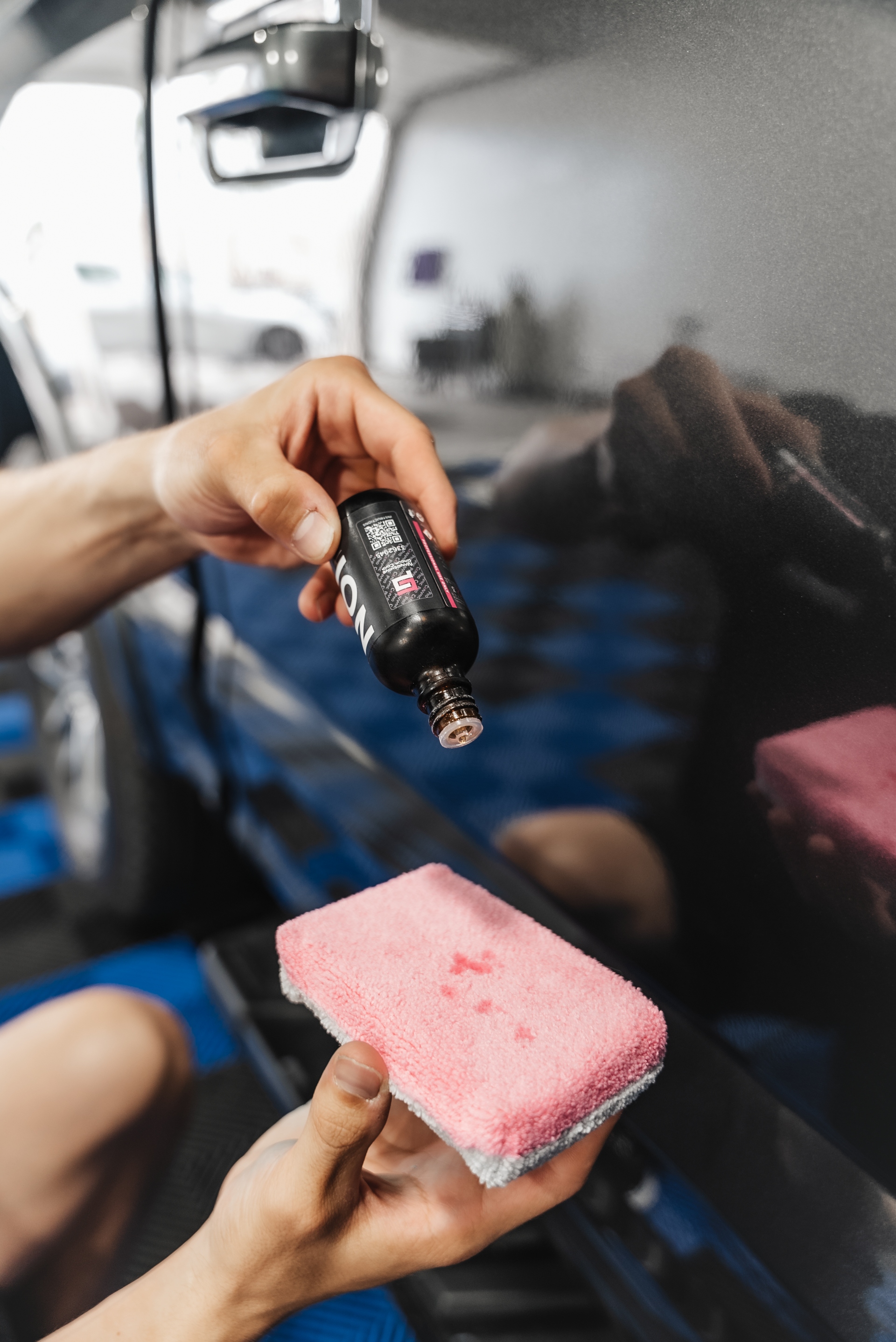 A person is holding a pink sponge and a bottle of polish.
