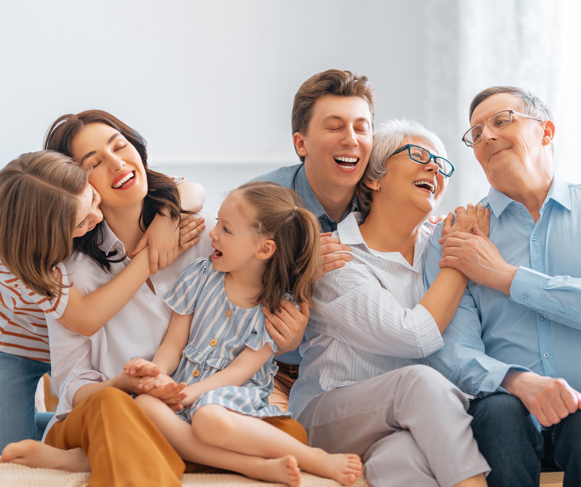 Family laughing and embracing on a sofa; a girl sits in the center.
