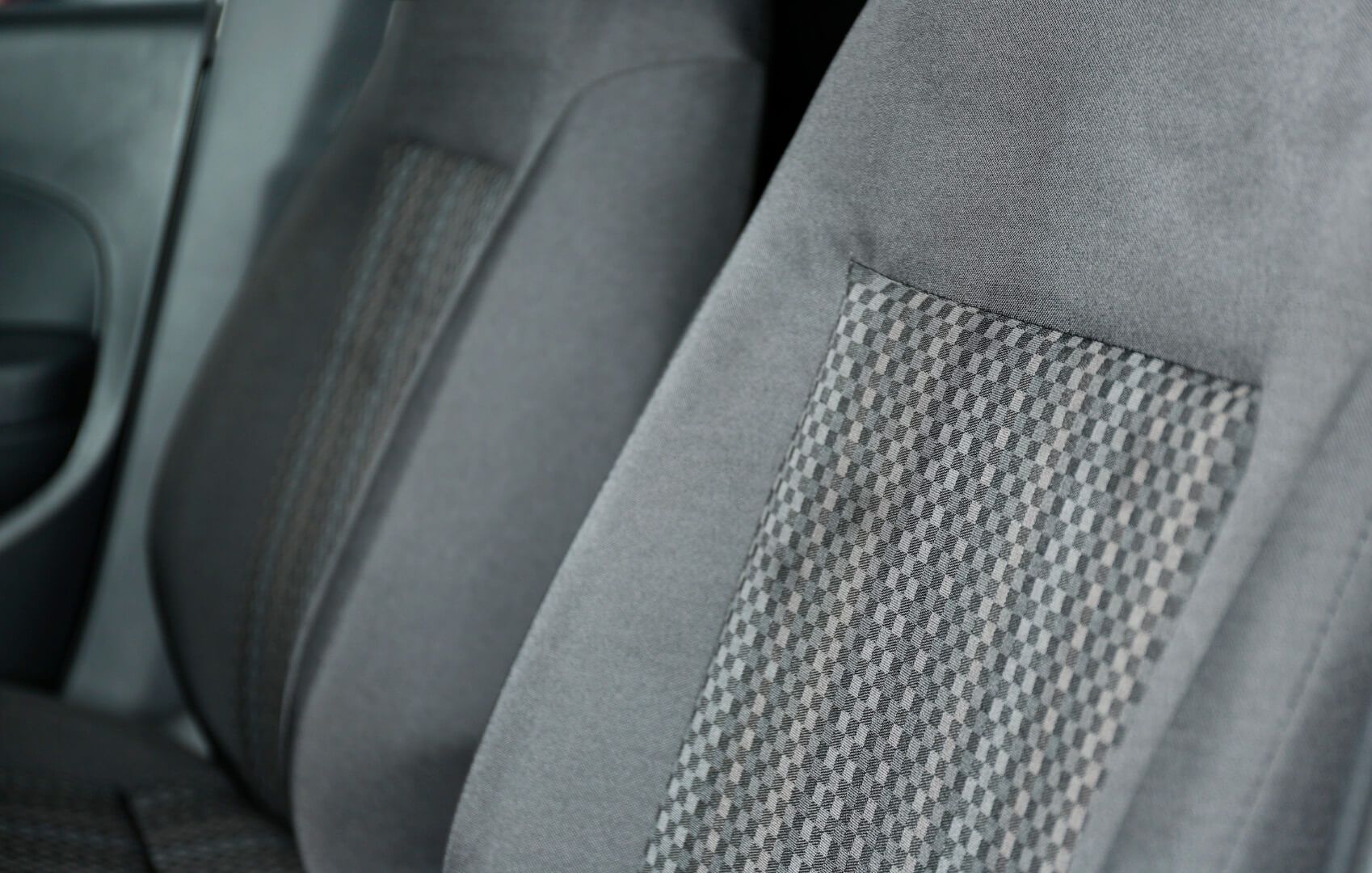 Primer plano de asientos de coche de tela gris con un estampado central texturizado a cuadros.