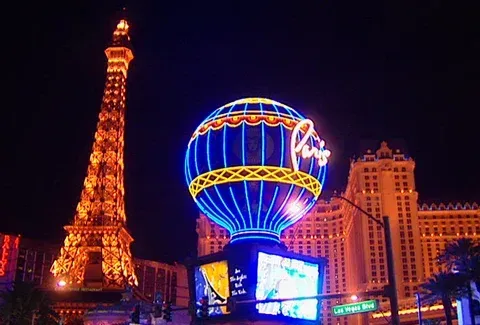 Eiffel Tower replica and hot air balloon sign at the Paris Las Vegas hotel, illuminated at night.