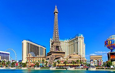 Las Vegas skyline with a replica Eiffel Tower, blue sky, water, and various buildings.