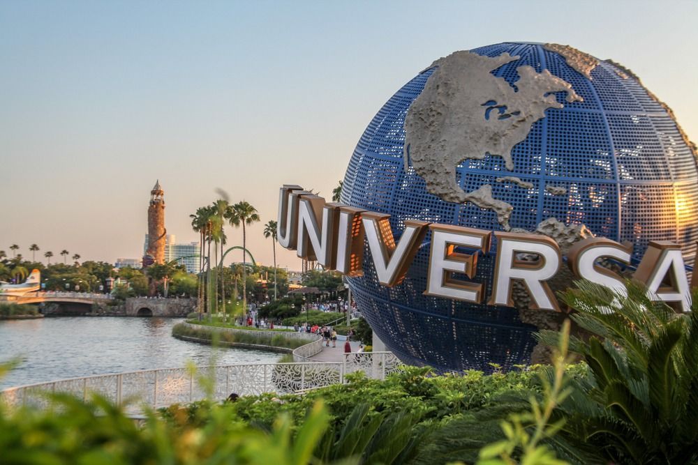 Universal Studios globe and sign with waterfront, tower, and palm trees.
