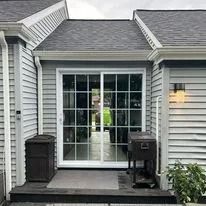 Back exterior of a house with sliding glass doors and a trash can.