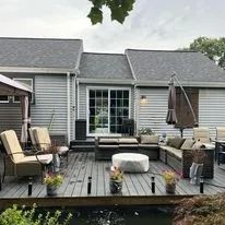 Patio with seating near a house. Tables, chairs, and a small pond are present.