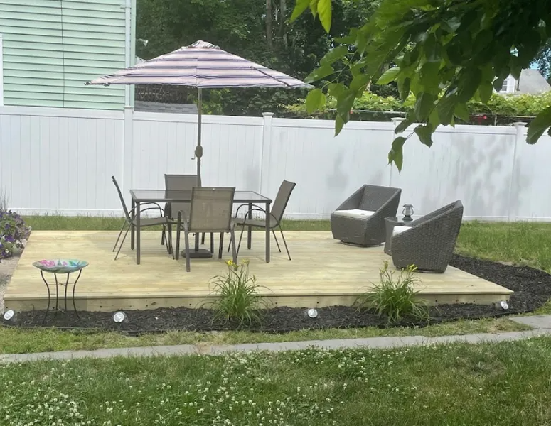 Blue house with wooden stairs leading to a white door. A window with an AC unit is also visible.