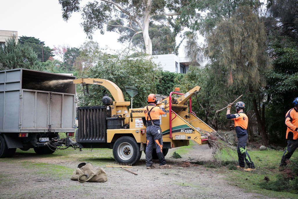 A group of men are working on a tree chipper in a yard.