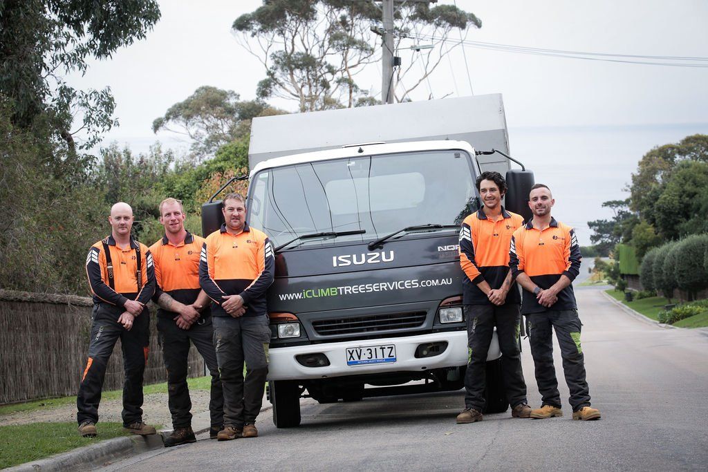 A group of men are standing in front of a truck.