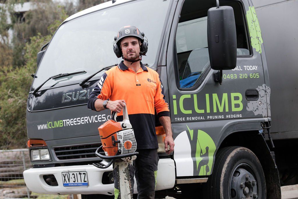 A man is standing in front of a truck holding a chainsaw.