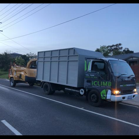 A truck with a chipper attached to it is parked on the side of the road.