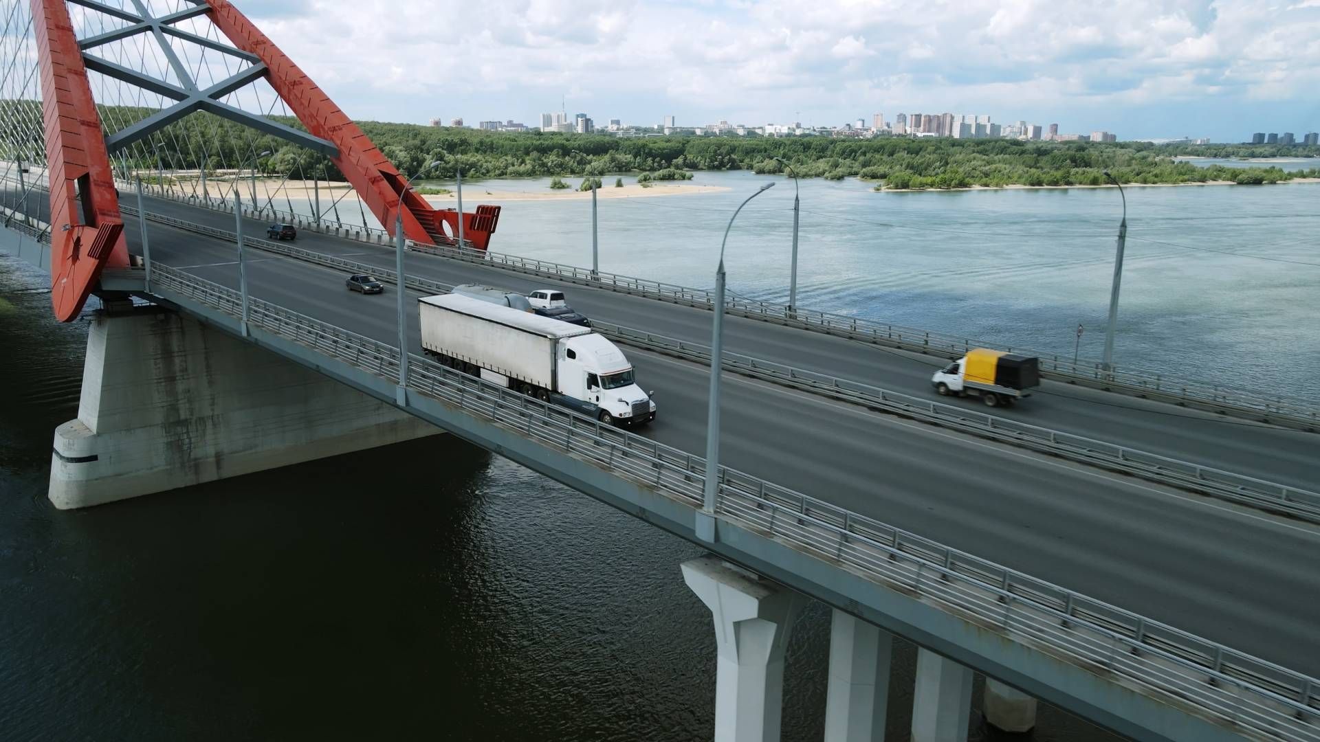 A red arched bridge with vehicles crossing over water.
