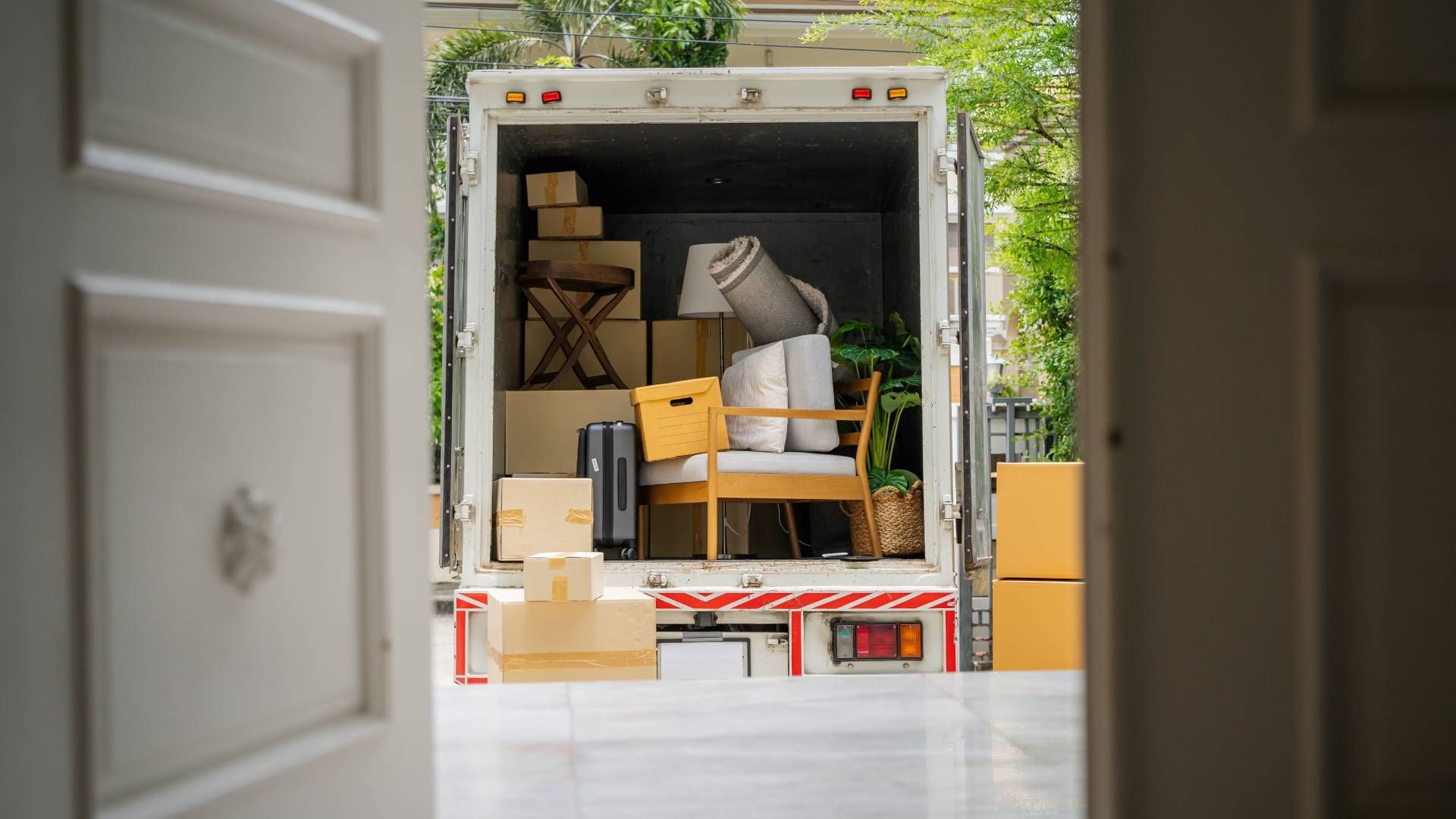Moving truck loaded with boxes and furniture, parked in front of a house.
