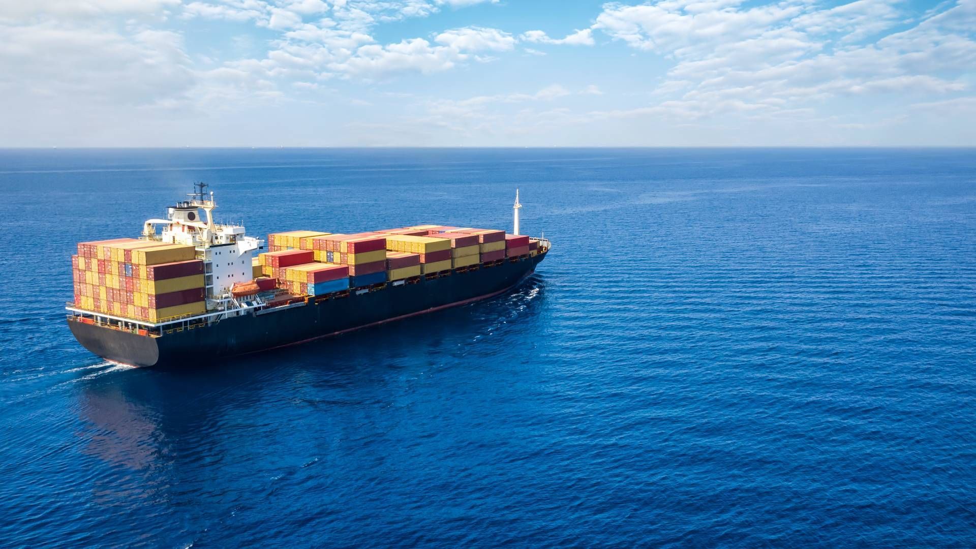 Cargo ship at sea, blue water, yellow and brown containers, sunny day.