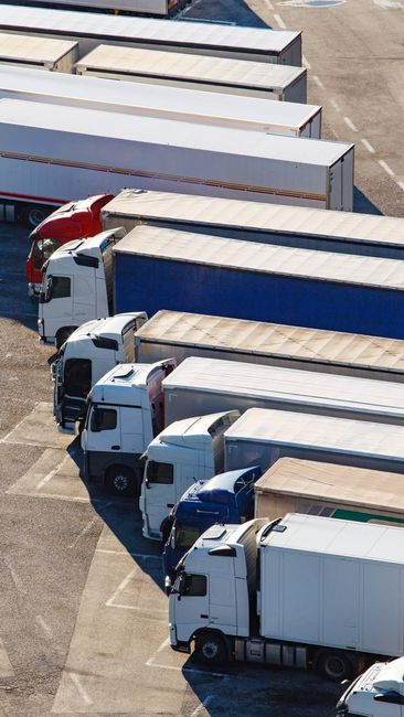 Trucks parked in a lot, various colors including red, white, and blue, arranged in a line.