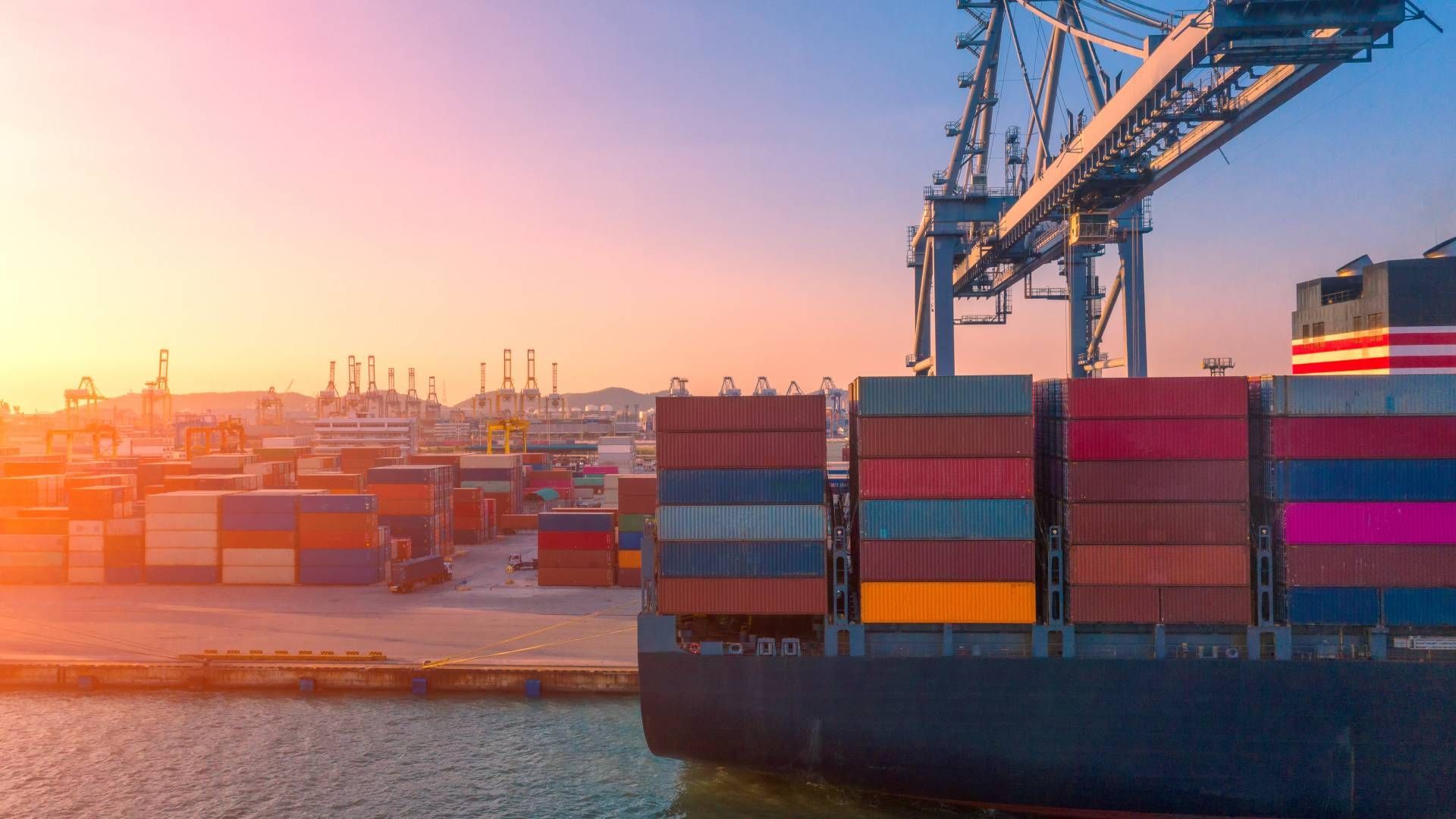 Shipping containers on a cargo ship at a port during sunset.