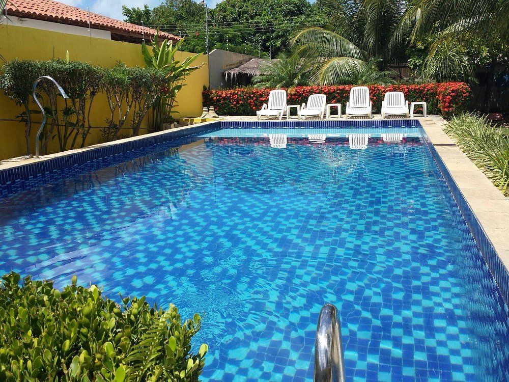 Uma grande piscina cercada por cadeiras e arbustos