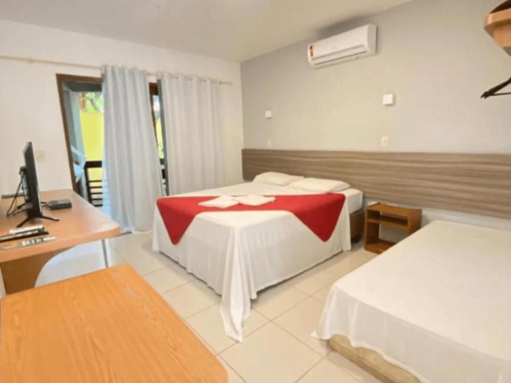 Um quarto de hotel com duas camas, uma escrivaninha e uma televisão.