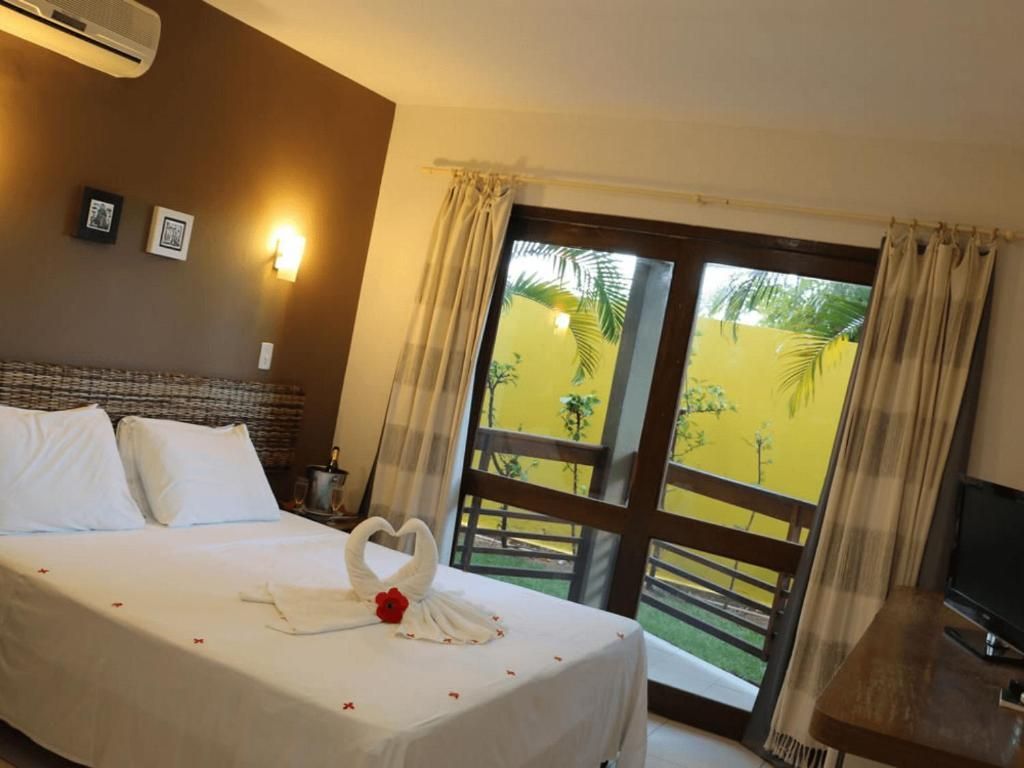 Um quarto de hotel com uma cama grande e uma porta de vidro deslizante