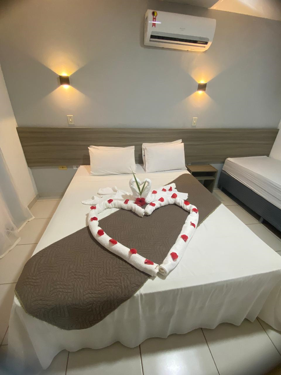 Uma cama com um coração feito de toalhas em um quarto de hotel