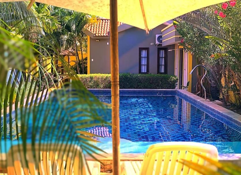 Uma piscina com um guarda-sol amarelo e cadeiras na frente dela.