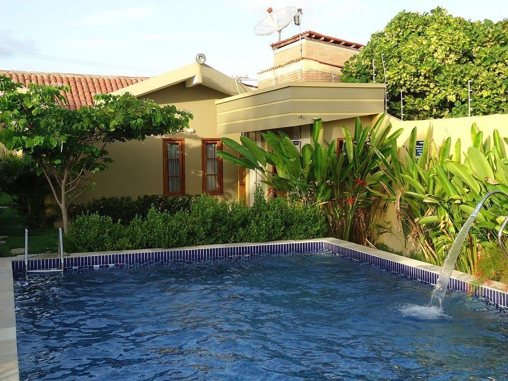 Uma piscina com uma fonte em frente a uma casa
