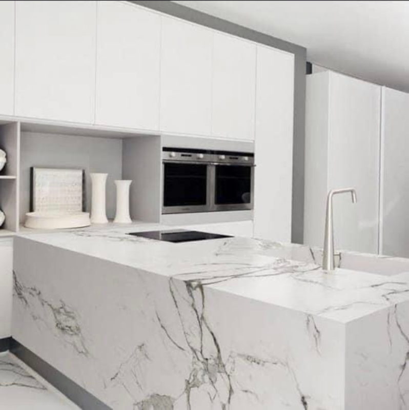 una cucina con armadi bianchi e una grande isola in marmo .