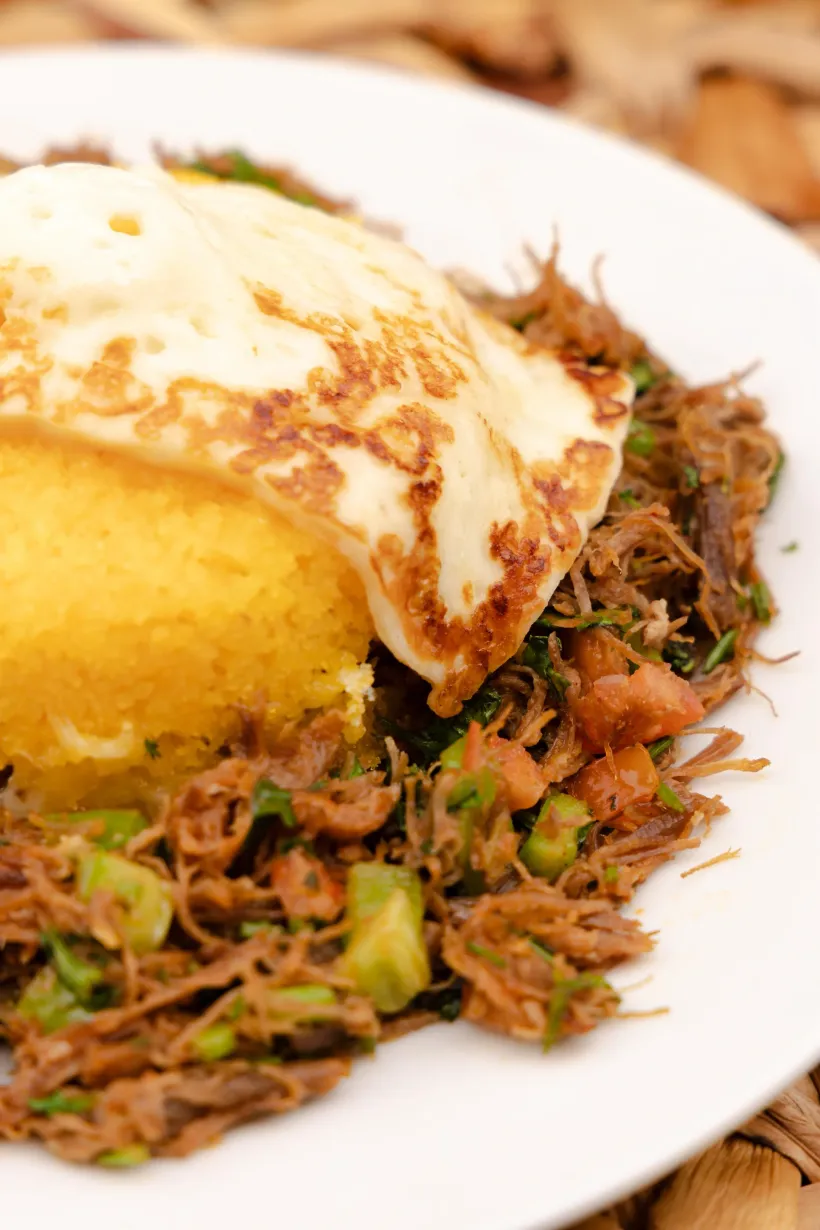 Um prato de carne desfiada, polenta e um ovo frito - Solar Café e Pousada