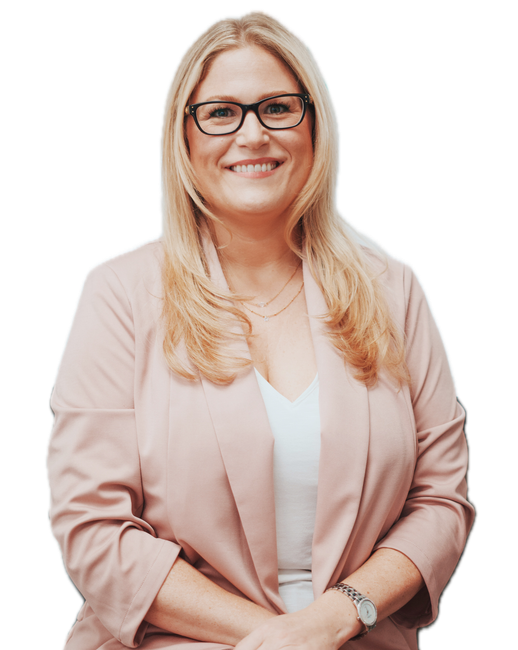 A woman wearing glasses and a pink jacket is smiling.