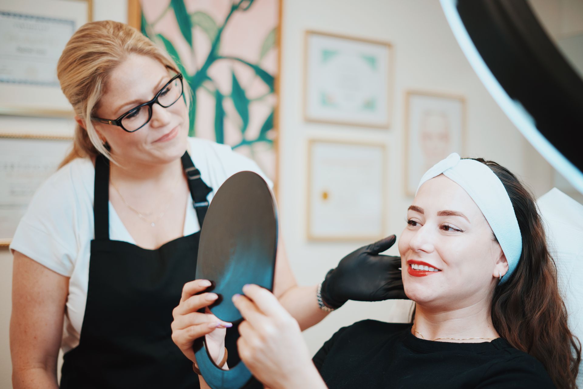 A woman is looking at her face in a mirror.