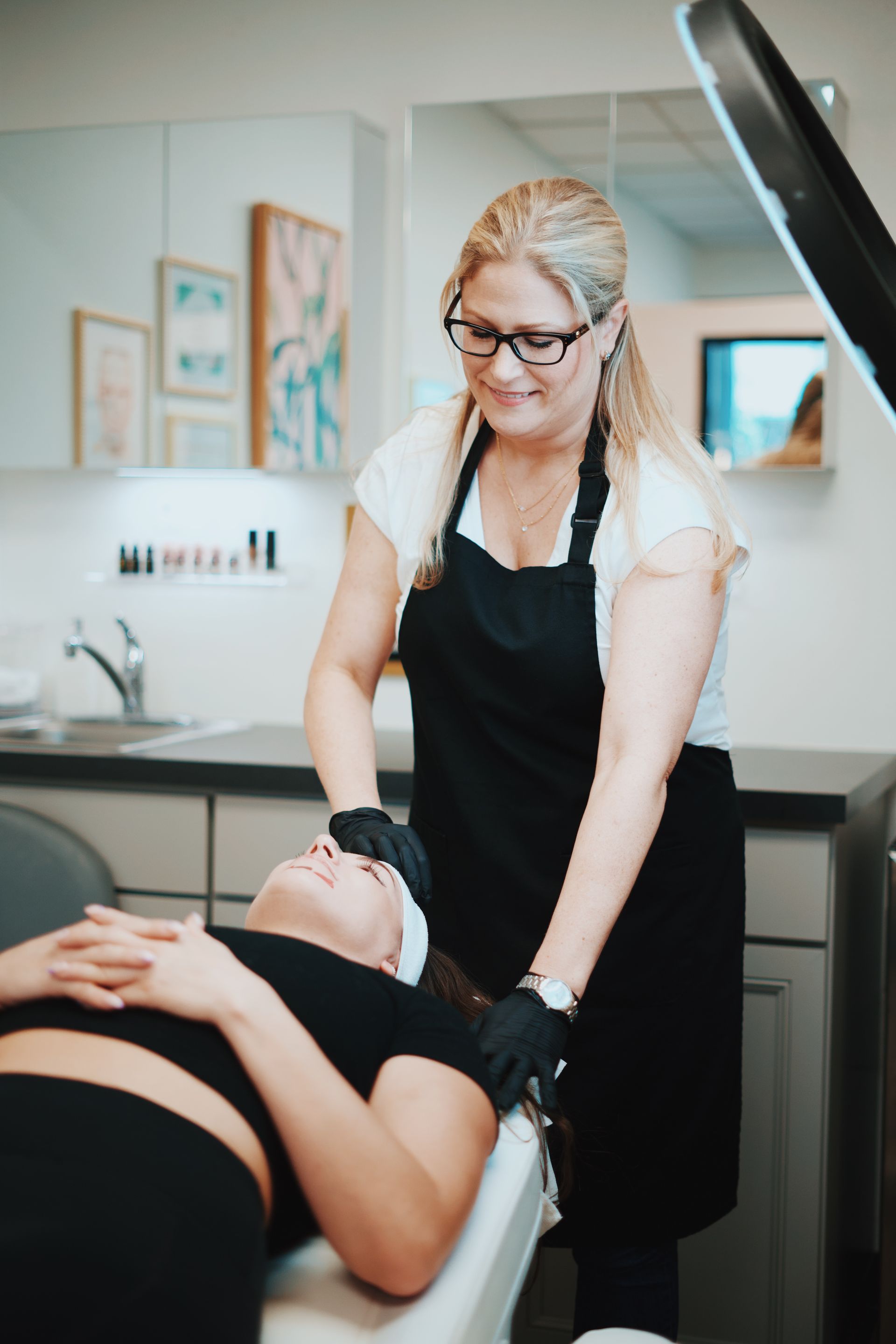 A woman is standing next to a woman laying in a chair.