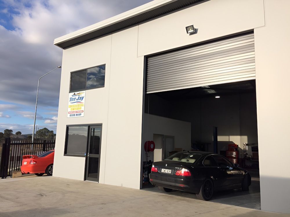 Two Cars Are Parked in Front of a Building With a Garage Door Open — TeeJay Mechanical Repairs In Beard, ACT