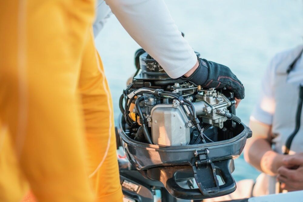 A Person is Holding an Outboard Motor on a Boat — TeeJay Mechanical Repairs In Canberra, ACT