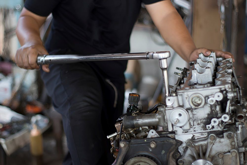 A Man is Working on a Car Engine With a Wrench — TeeJay Mechanical Repairs In Beard, ACT